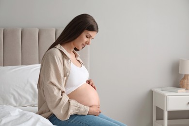 Photo of Beautiful pregnant woman on bed at home