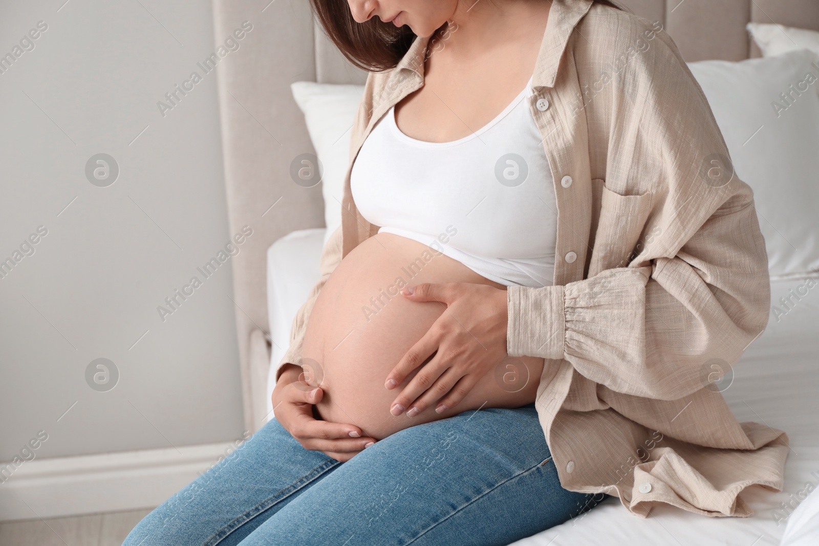 Photo of Pregnant woman on bed at home, closeup