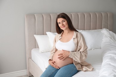 Beautiful pregnant woman on bed at home