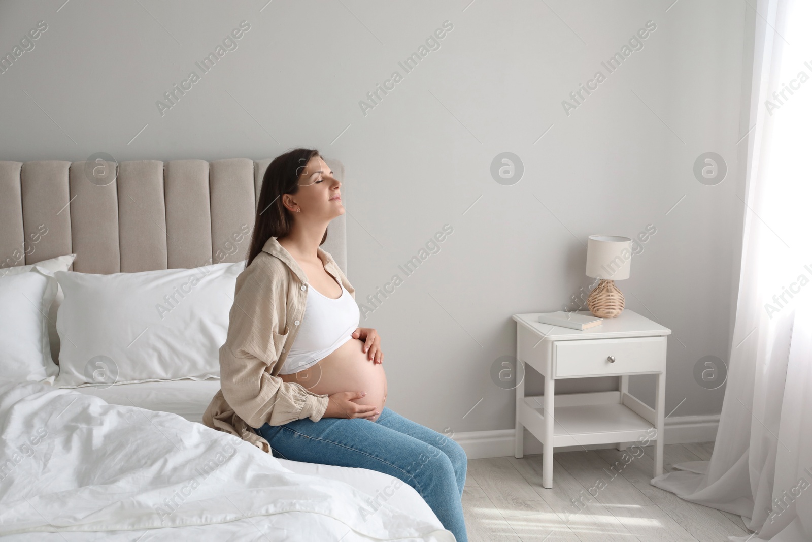 Photo of Beautiful pregnant woman on bed at home