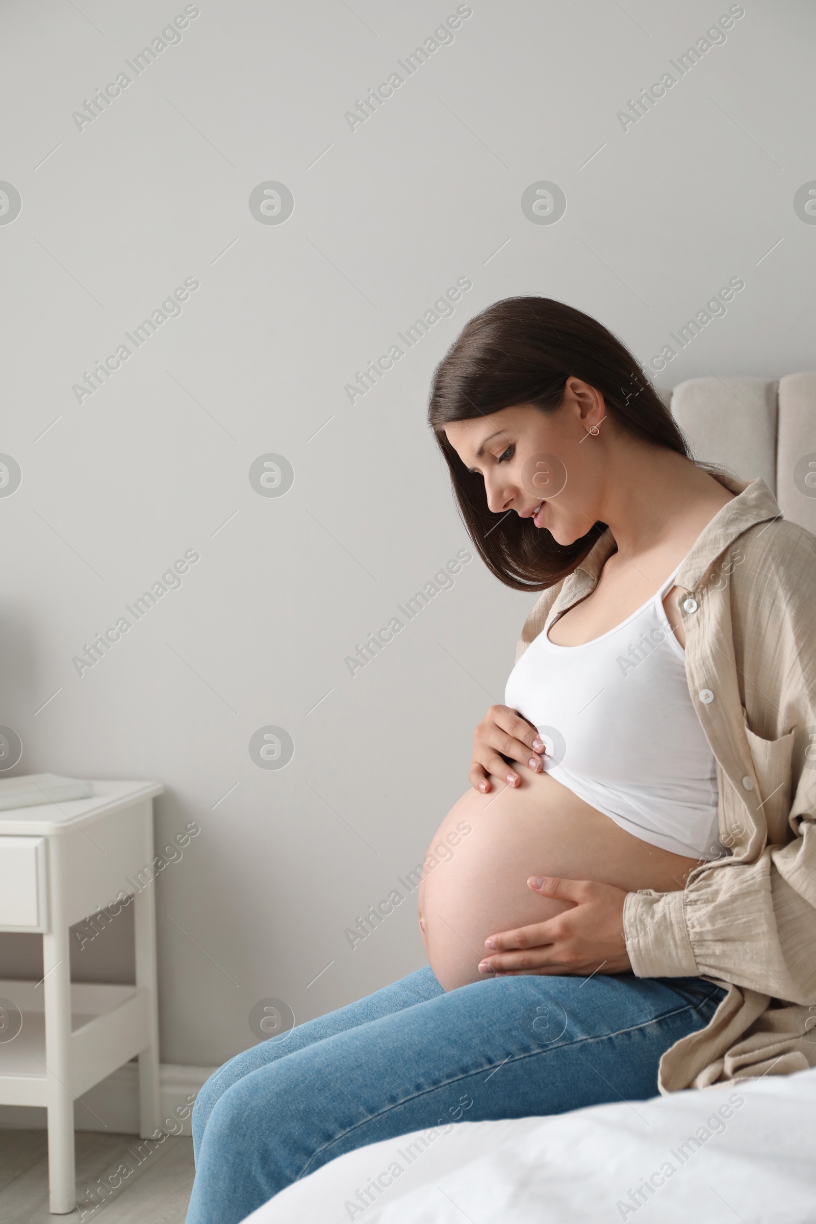 Photo of Beautiful pregnant woman on bed at home