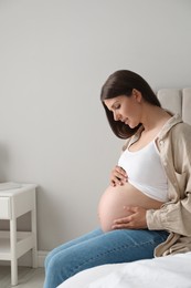 Beautiful pregnant woman on bed at home