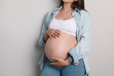 Pregnant woman on gray background, closeup view