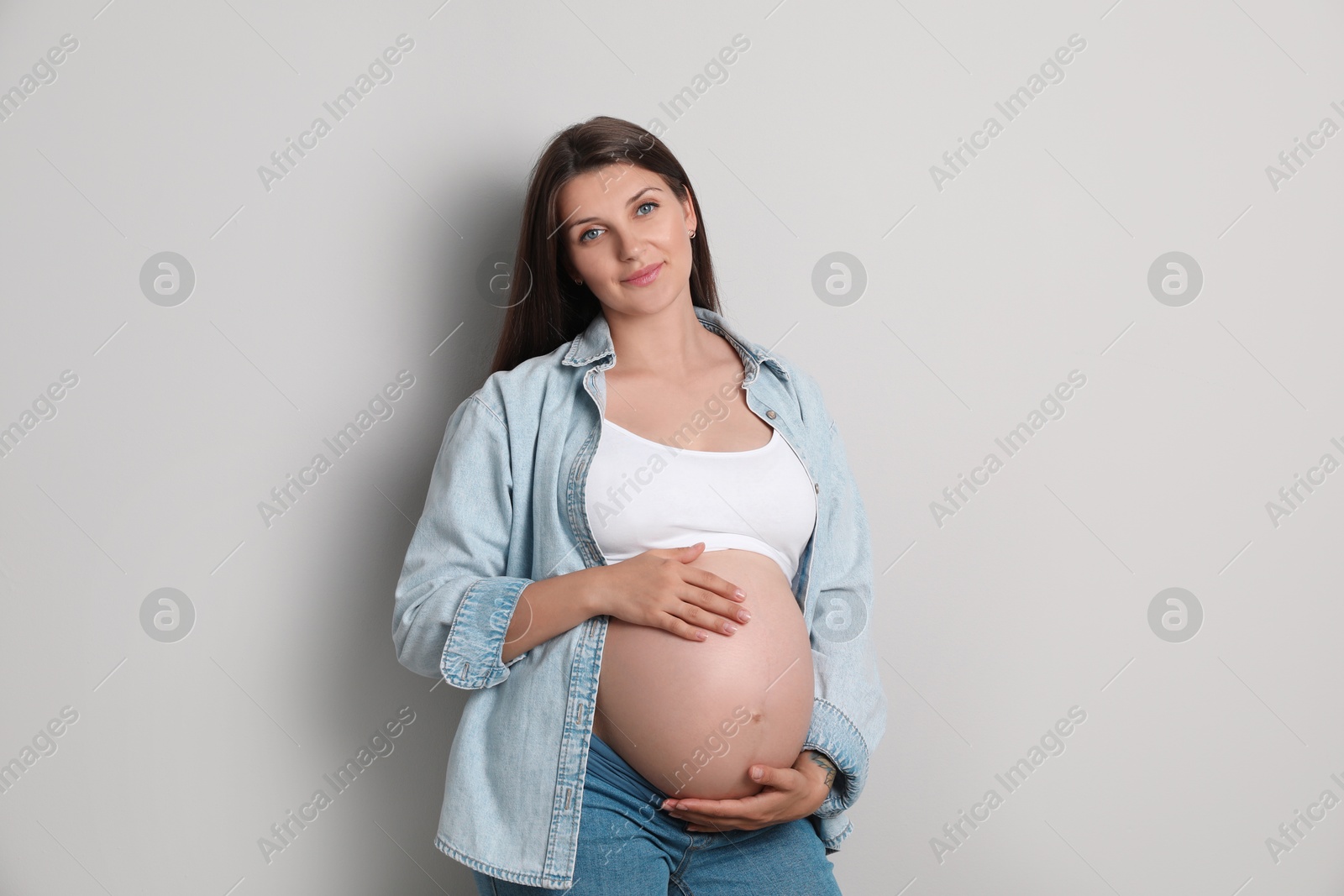 Photo of Portrait of beautiful pregnant woman on gray background