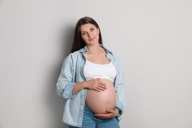 Portrait of beautiful pregnant woman on gray background