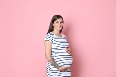 Portrait of beautiful pregnant woman on pink background