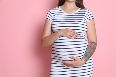 Pregnant woman on pink background, closeup. Space for text