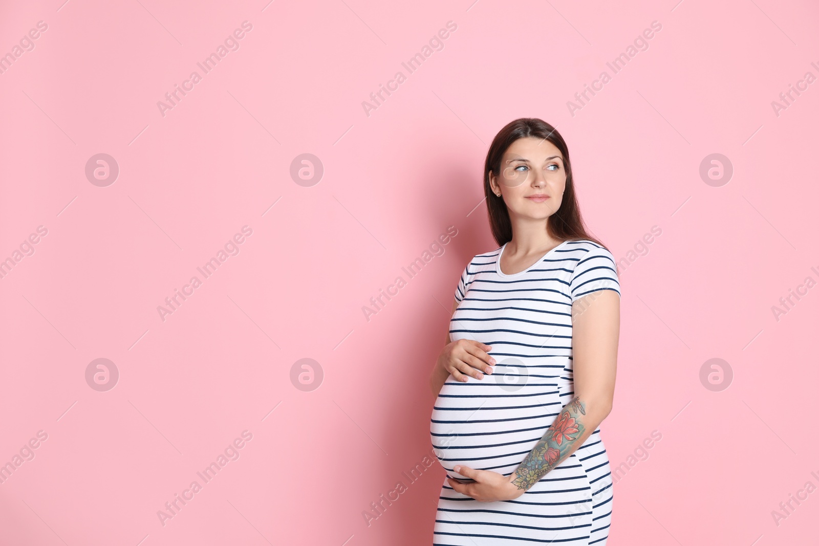 Photo of Beautiful pregnant woman on pink background, space for text