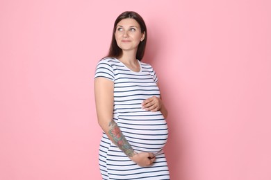 Portrait of beautiful pregnant woman on pink background