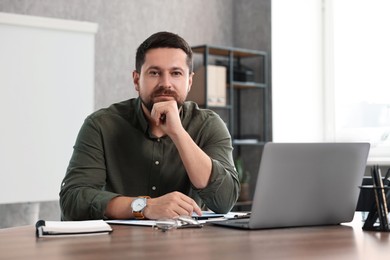 Photo of Consultant at table with laptop in office