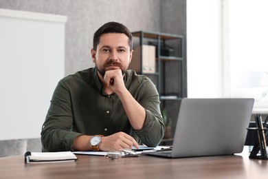 Consultant at table with laptop in office