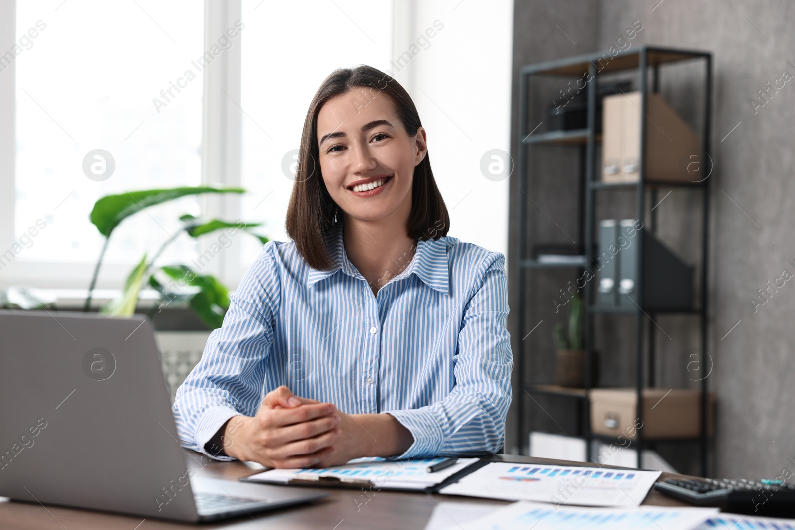 Photo of Consultant at table with documents and laptop in office