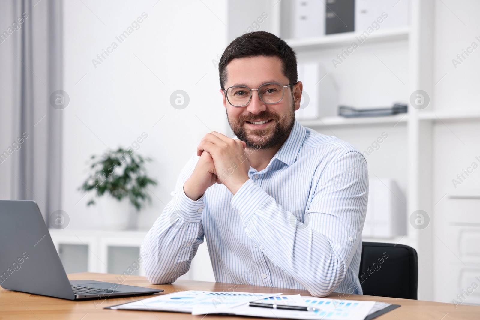 Photo of Consultant at table with laptop and documents in office