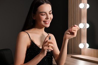 Photo of Smiling woman spraying perfume in makeup room