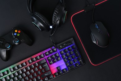 Computer mouse, RGB keyboard, game controller and headset on black background, flat lay