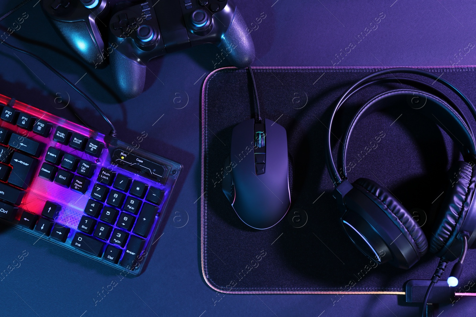 Photo of Computer mouse, RGB keyboard, game controllers and headset on black background, top view