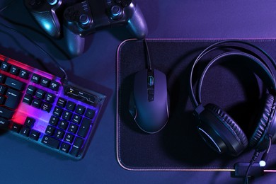 Photo of Computer mouse, RGB keyboard, game controllers and headset on black background, top view