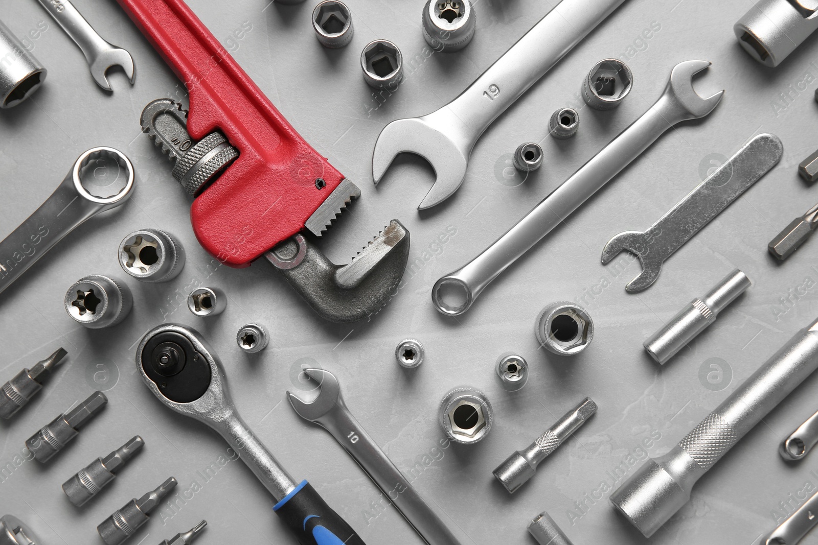 Photo of Different auto mechanic's tools on grey table, flat lay