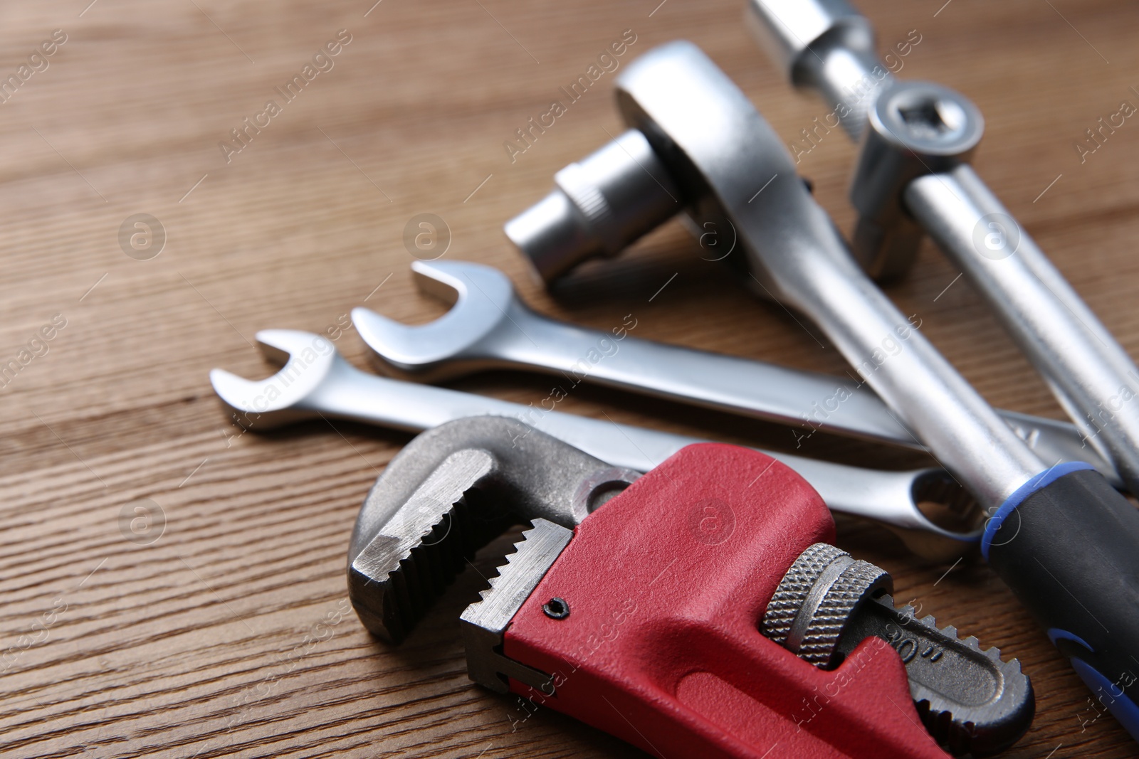 Photo of Different auto mechanic's tools on wooden table, closeup