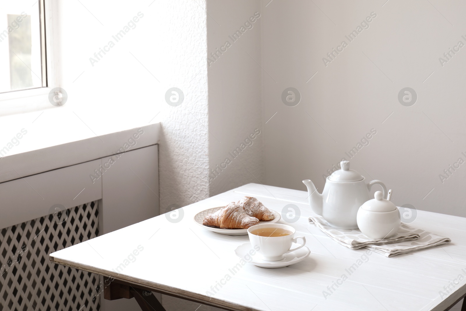 Photo of Croissants and tea on table in studio. Professional food photography