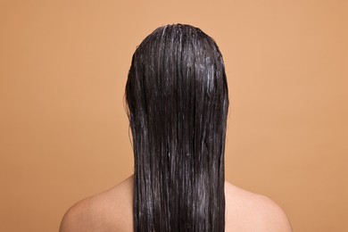 Photo of Woman with applied hair mask on beige background, back view
