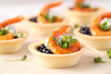 Photo of Delicious canapes with shrimps and black caviar on light table, closeup