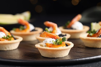 Delicious canapes with shrimps and black caviar on table, closeup