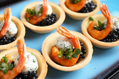 Photo of Delicious canapes with shrimps and black caviar on plate, closeup