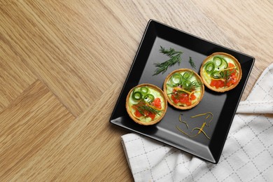 Photo of Delicious canapes with salmon on wooden table, top view. Space for text