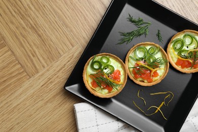 Delicious canapes with salmon on wooden table, top view. Space for text