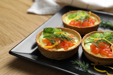 Photo of Delicious canapes with salmon on wooden table, closeup