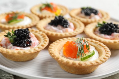 Photo of Delicious canapes with salmon and caviar on plate, closeup