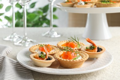 Photo of Delicious canapes with shrimps, salmon and caviar on beige textured table, closeup