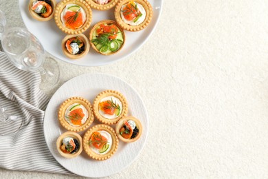 Photo of Delicious canapes with shrimps, salmon and caviar on beige textured table, flat lay. Space for text