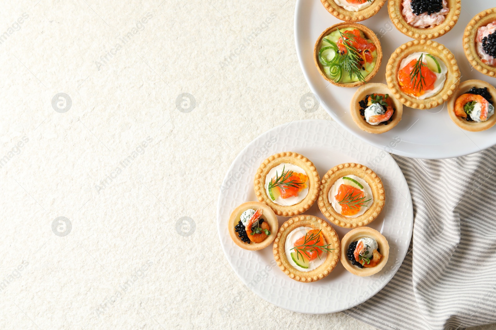 Photo of Delicious canapes with shrimps, salmon and caviar on beige textured table, flat lay. Space for text