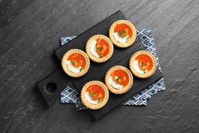 Photo of Delicious canapes with shrimps, red caviar and cream cheese on dark textured table, top view