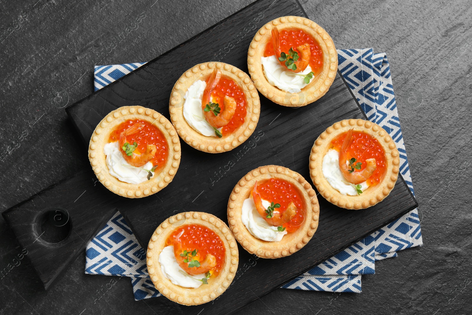 Photo of Delicious canapes with shrimps, red caviar and cream cheese on dark textured table, top view