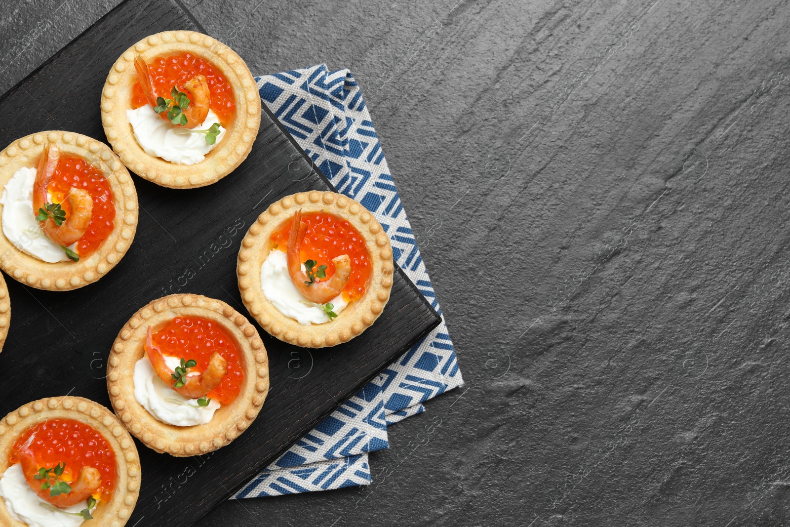 Photo of Delicious canapes with shrimps, red caviar and cream cheese on dark textured table, top view. Space for text