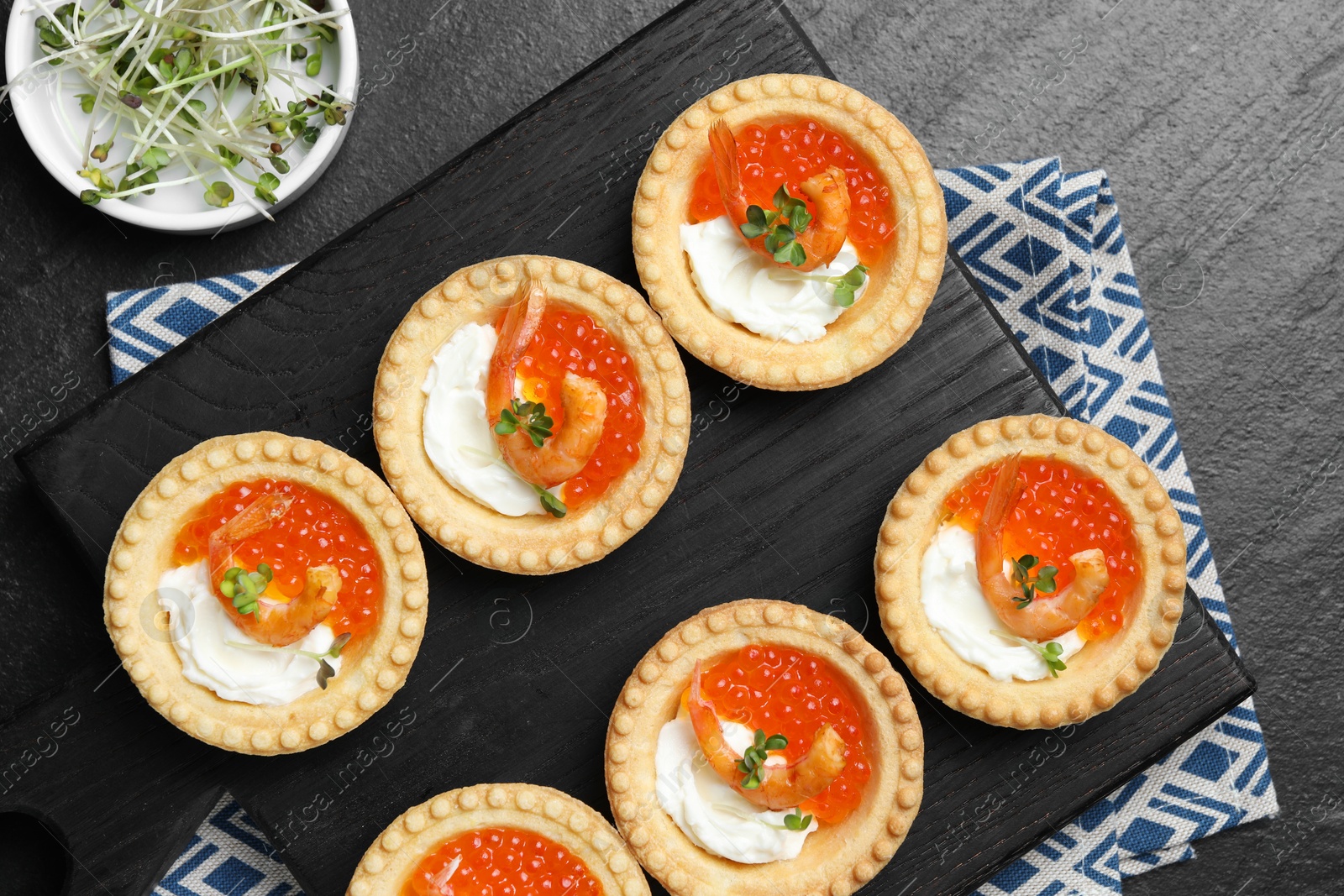 Photo of Delicious canapes with shrimps, red caviar and cream cheese on dark textured table, flat lay