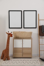 Photo of Child's room interior with modern furniture, toy giraffe and empty frames on wall