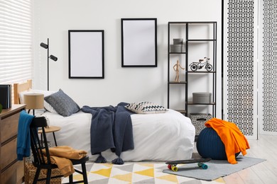 Photo of Teen's room interior with modern furniture and empty frames on wall