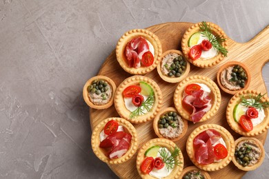 Photo of Delicious canapes with jamon, pate and dry smoked sausages on grey textured table, top view