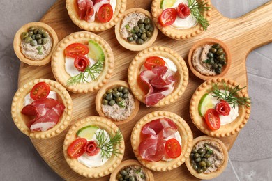 Photo of Delicious canapes with jamon, pate and dry smoked sausages on grey textured table, top view