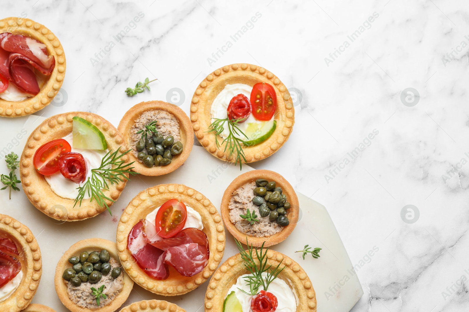 Photo of Different delicious canapes on white marble table, flat lay