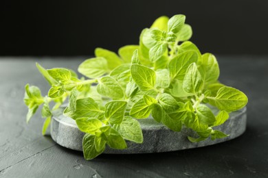 Photo of Sprigs of fresh green oregano on dark gray textured table, closeup