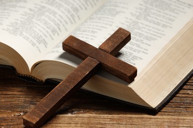 Bible and cross on wooden table, closeup. Religion of Christianity