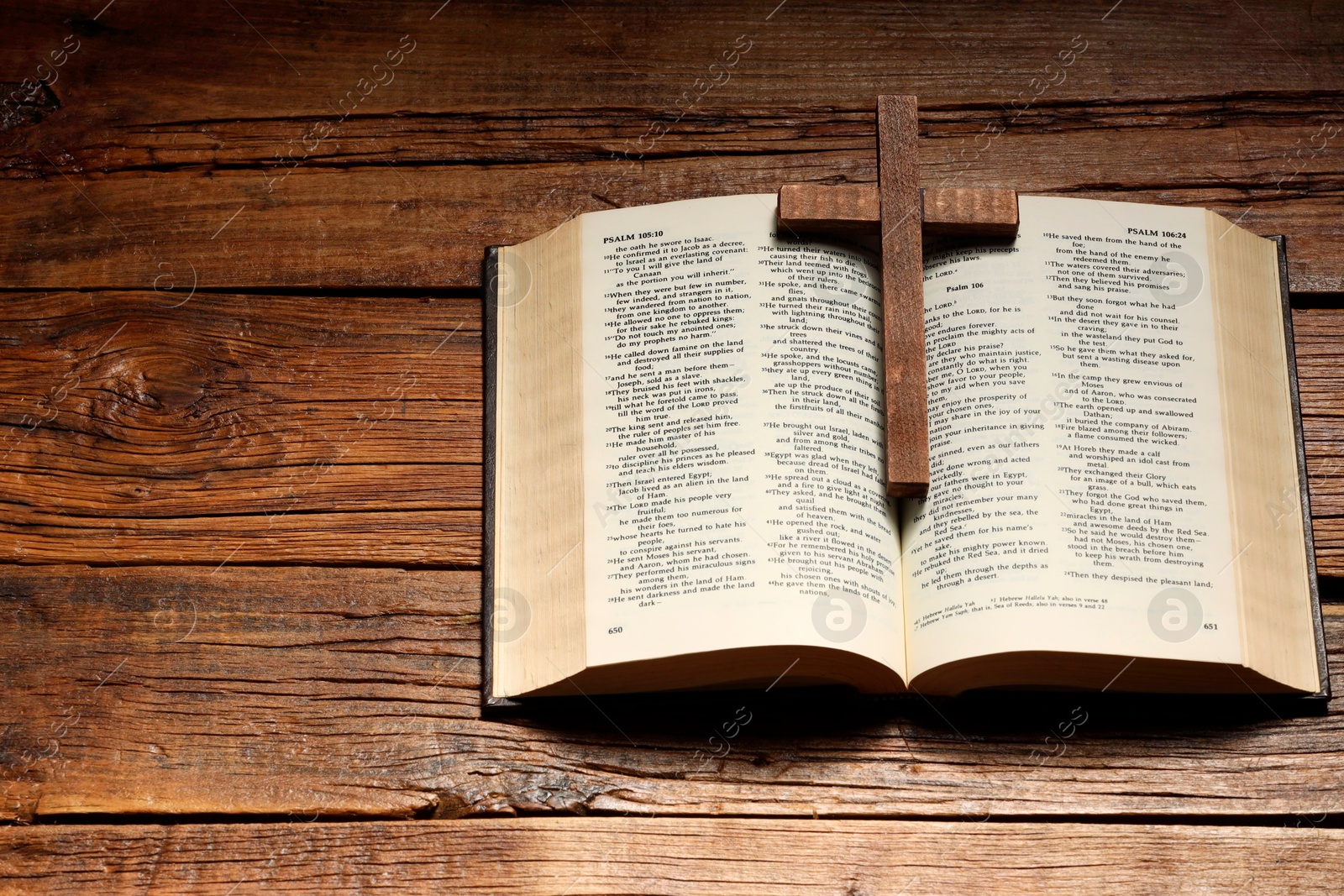 Photo of Bible and cross on wooden table, above view with space for text. Religion of Christianity