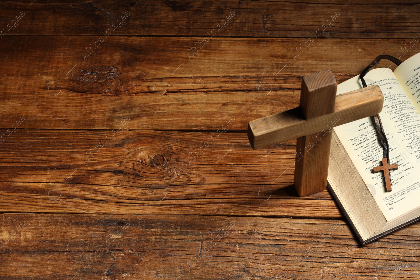 Photo of Cross and Bible on wooden table, above view with space for text. Religion of Christianity