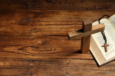 Cross and Bible on wooden table, above view with space for text. Religion of Christianity