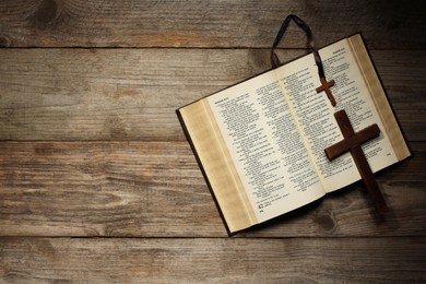 Photo of Bible and crosses on wooden table, top view with space for text. Religion of Christianity